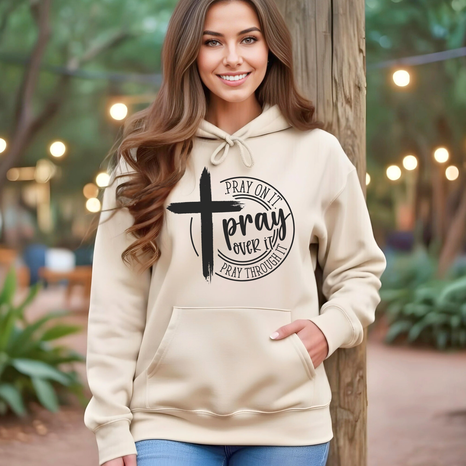 Woman wearing black Pray Over It Christian hoodie with cross design, front view