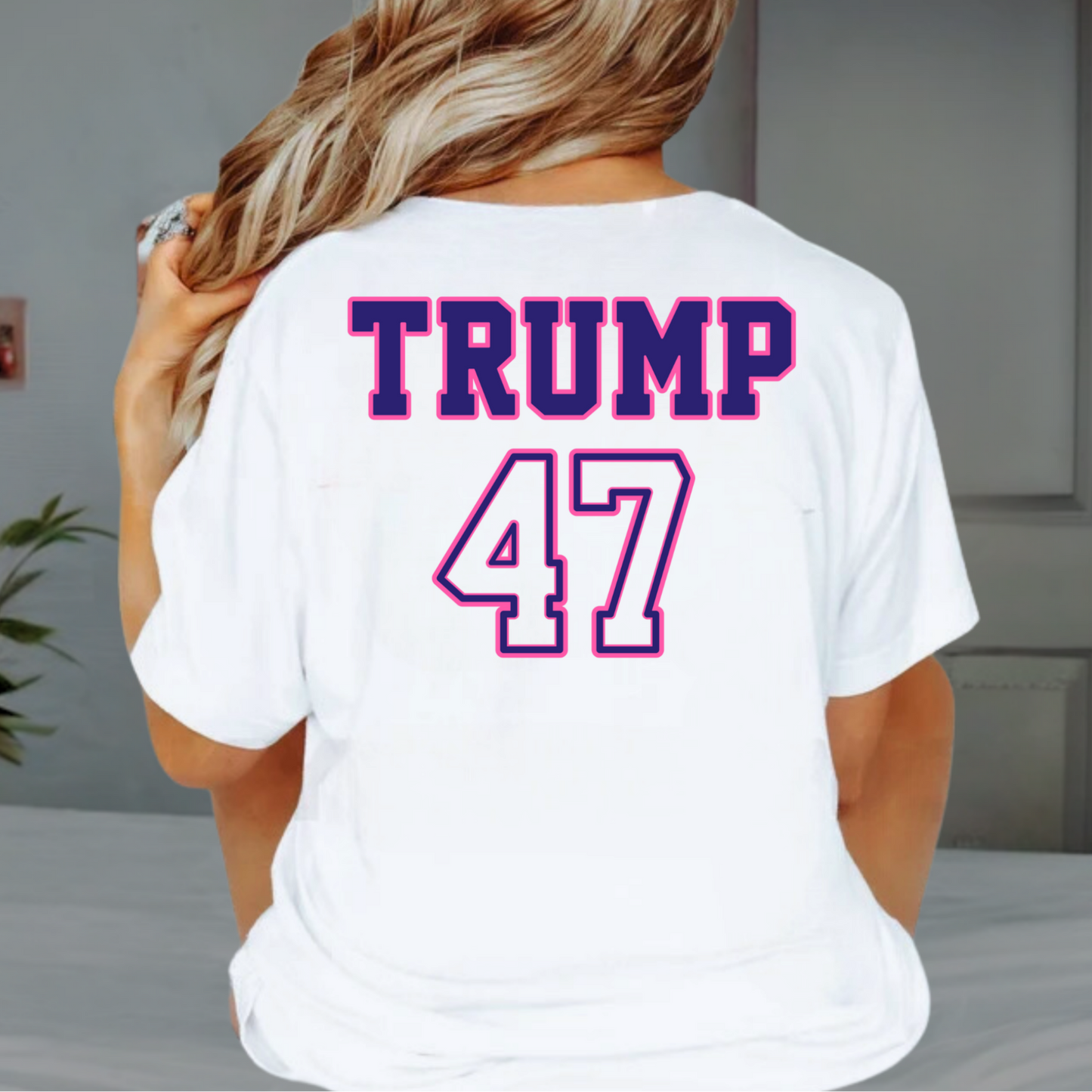 Woman wearing white Trump 47 shirt with Make America Trump Again circle design, sitting indoors