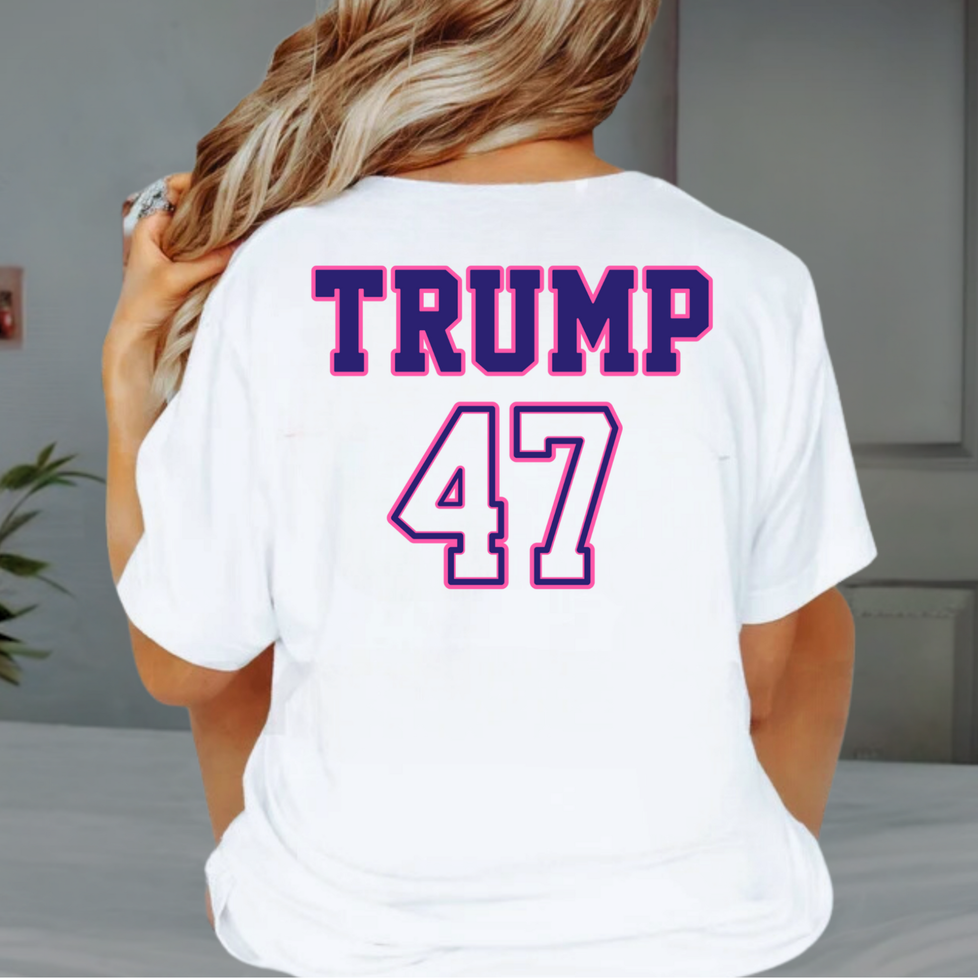 Woman wearing white Trump 47 shirt with Make America Trump Again circle design, sitting indoors