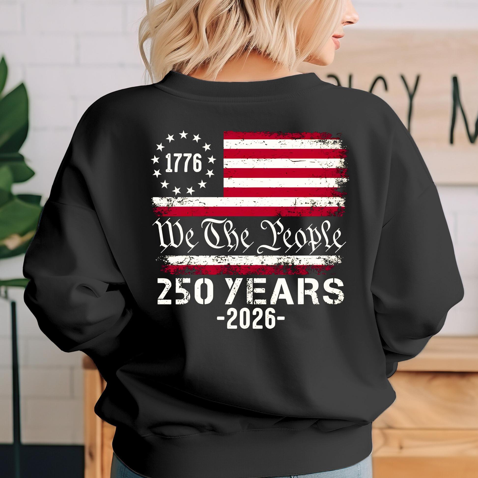 Person wearing a black sweatshirt with a U.S. flag and text design.