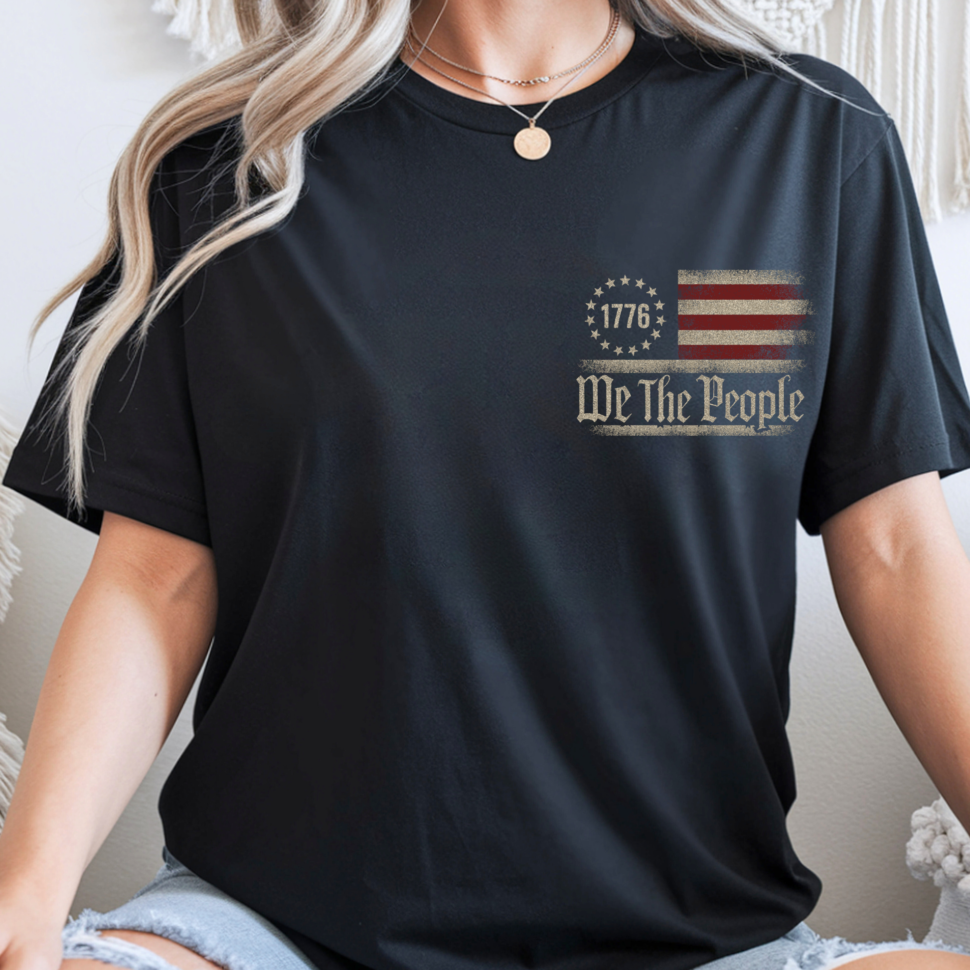 Person wearing a black t-shirt with 'We The People' and American flag design.
