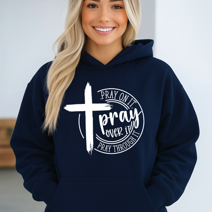 Person wearing a navy hoodie with a cross and text design on a plain background