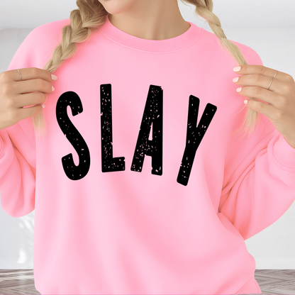 Woman wearing a pink sweatshirt with 'SLAY' printed in black letters.