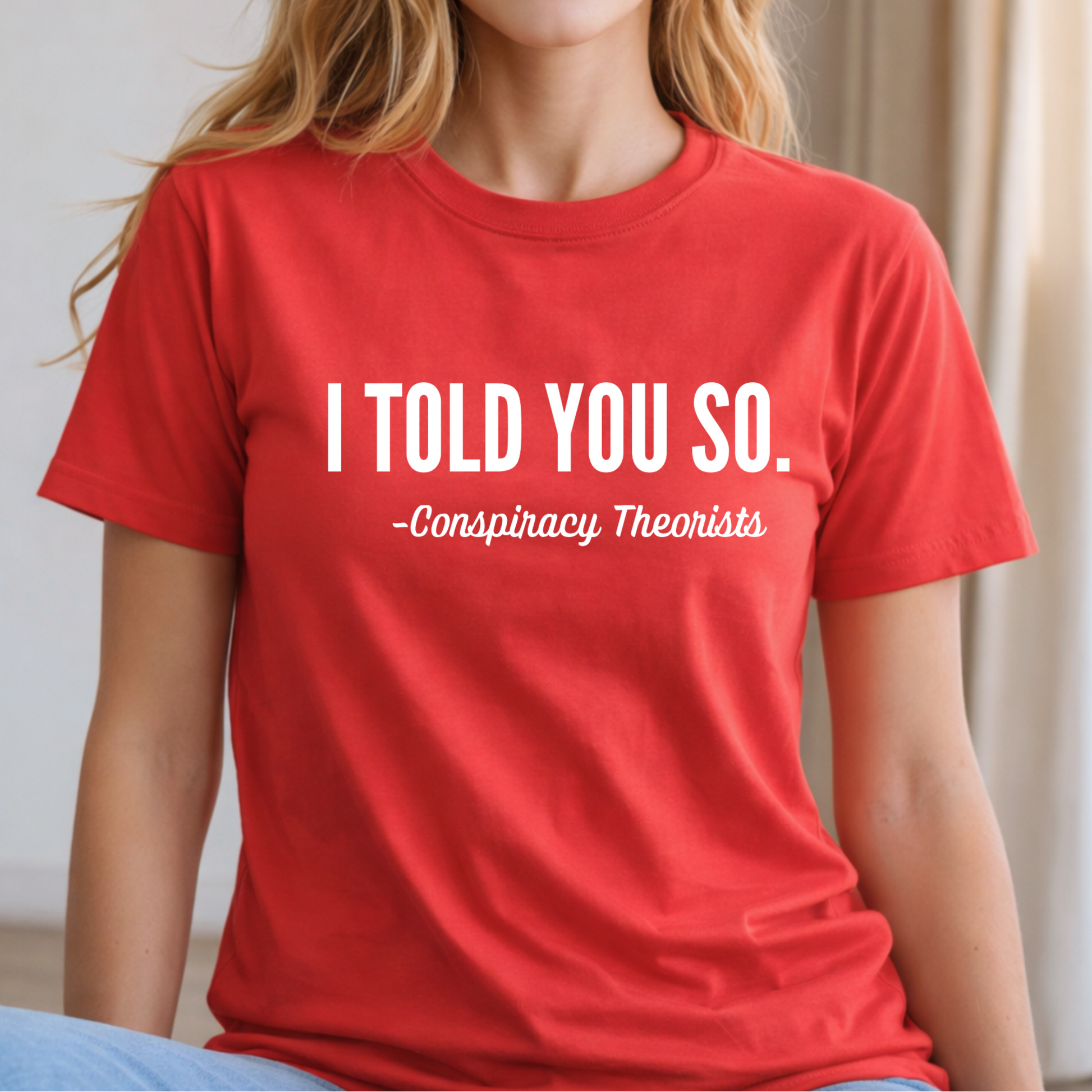 Woman wearing a red t-shirt with text 'I TOLD YOU SO. -Conspiracy Theorists'.