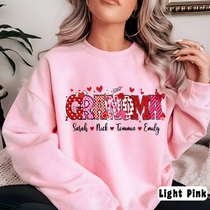 A woman sitting wearing a pink custom sweatshirt with 'Gramma' printed on the front along with hearts and the names 'Sarah, Nick, Tatum, Emily'.