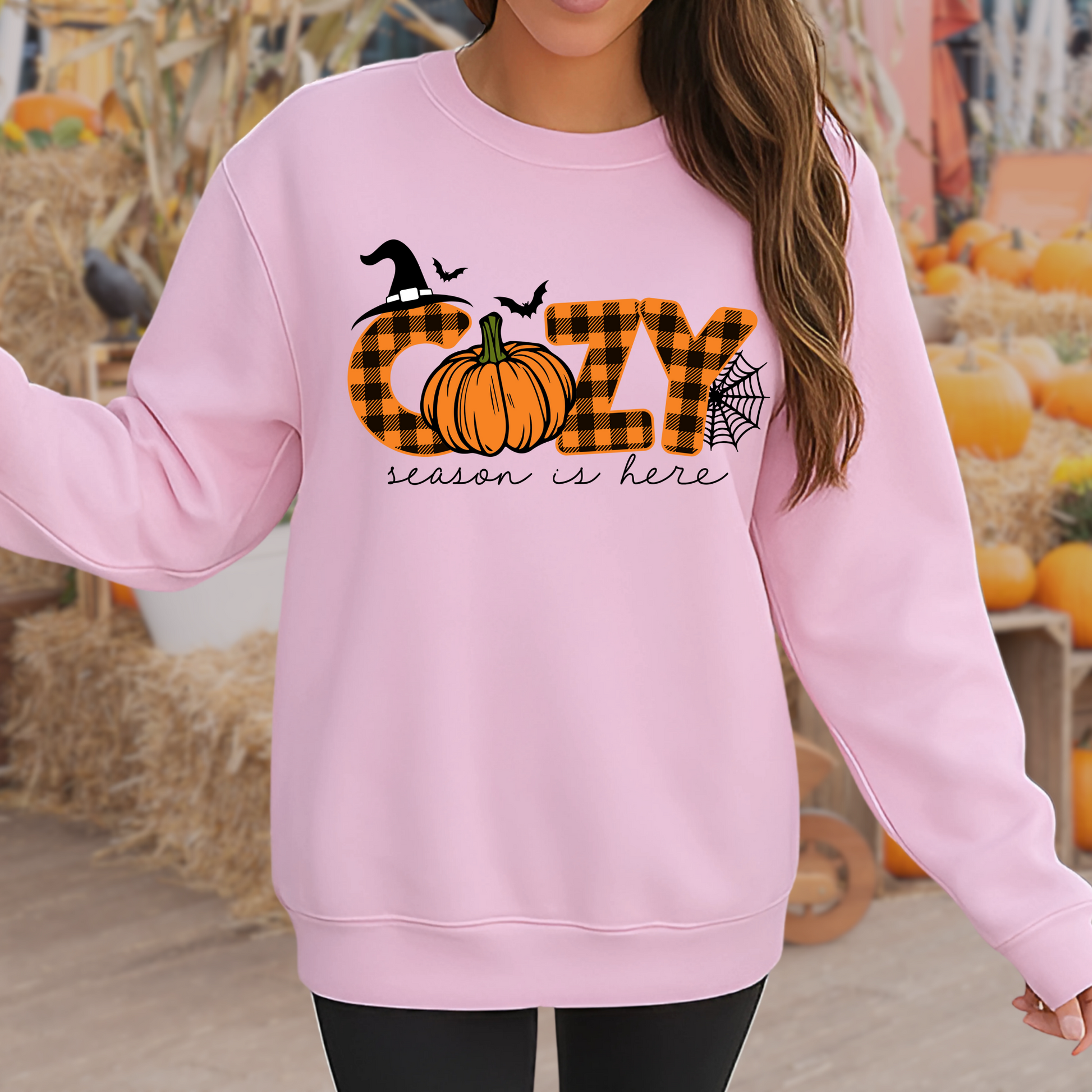 Pink fall sweatshirt with Halloween-themed “Cozy” design, shown at pumpkin patch