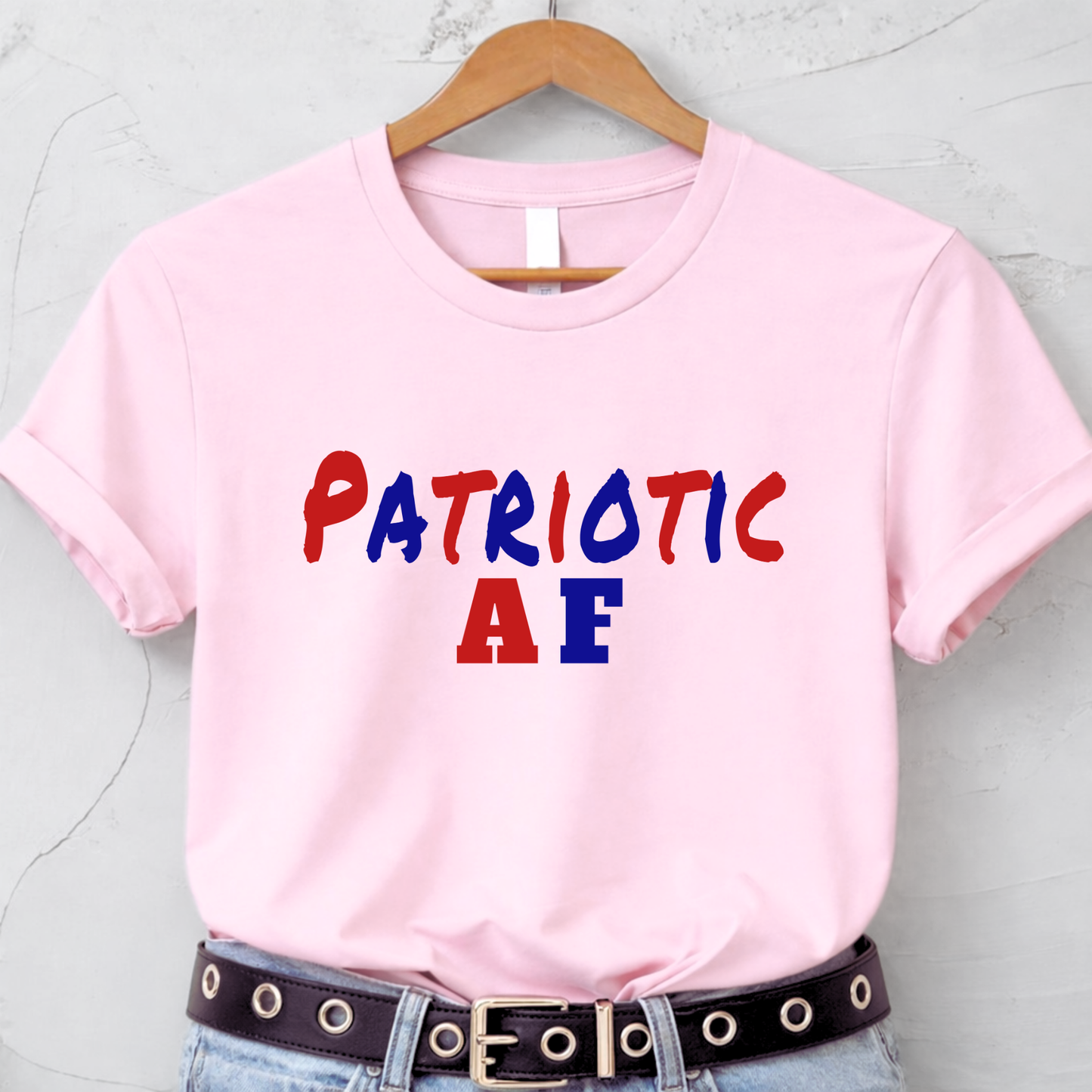 Pink patriotic AF graphic t-shirt hanging on hanger flat lay