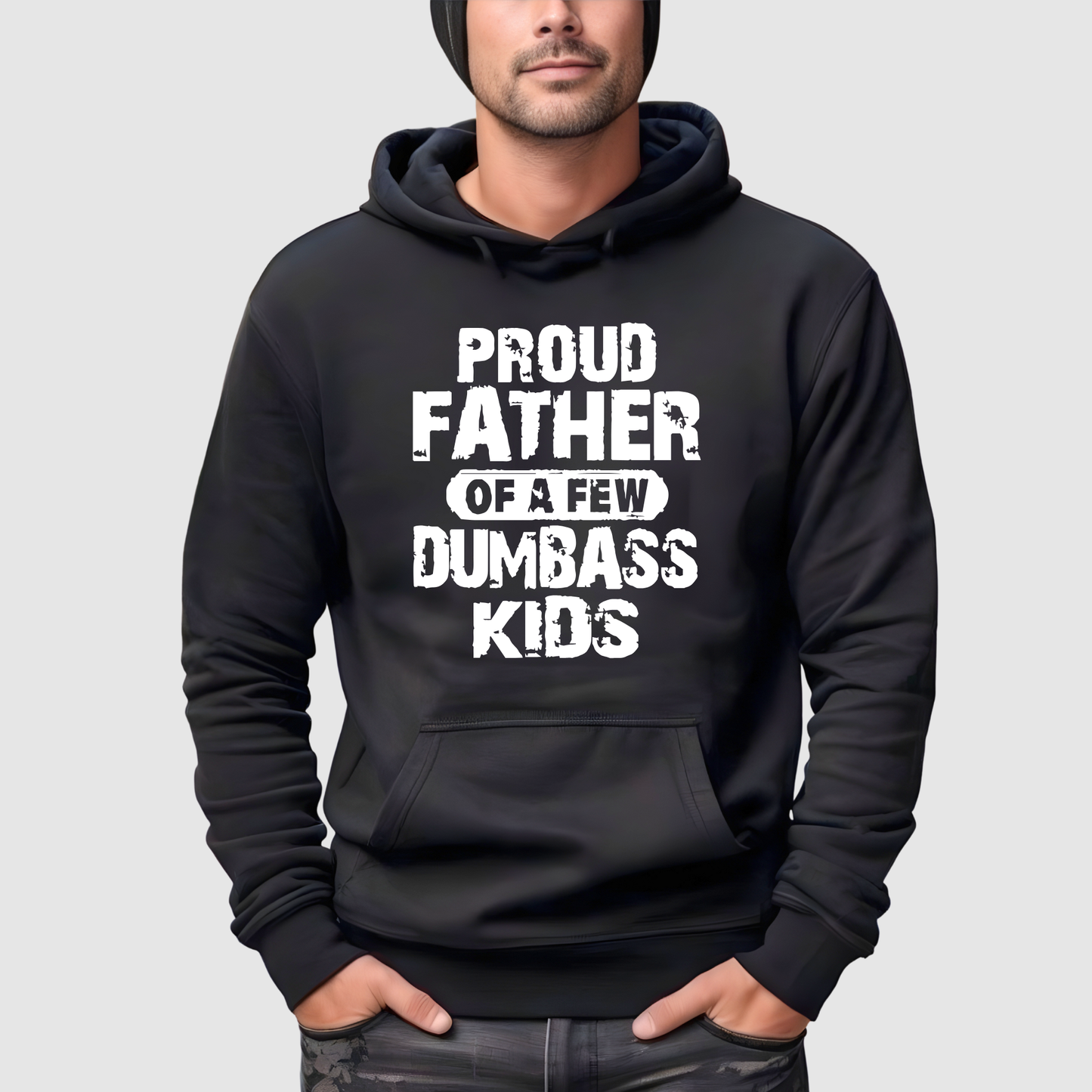 Black hoodie with white text 'PROUD FATHER OF A FEW DUMBBASS KIDS' worn by a person on a light gray background