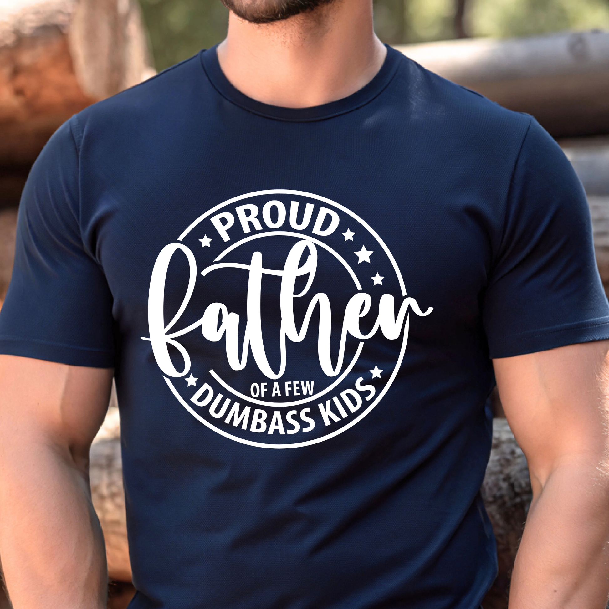 Navy blue t-shirt with white text 'Proud father of a few dumbass kids' worn by a person.