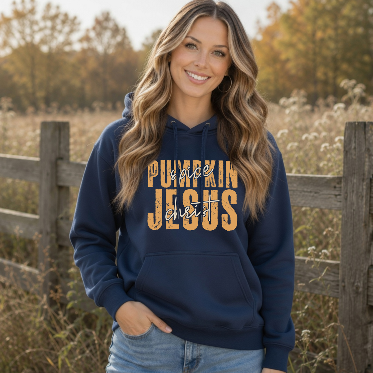 Woman wearing a navy Pumpkin Spice and Jesus Christ hoodie in a warm autumn field setting