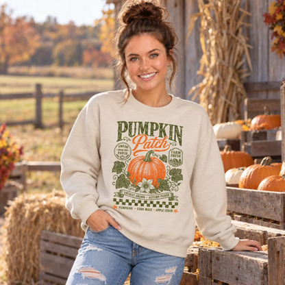 Woman wearing a sand sweatshirt with vintage Pumpkin Patch pumpkin and floral design beside pumpkins at a fall farm