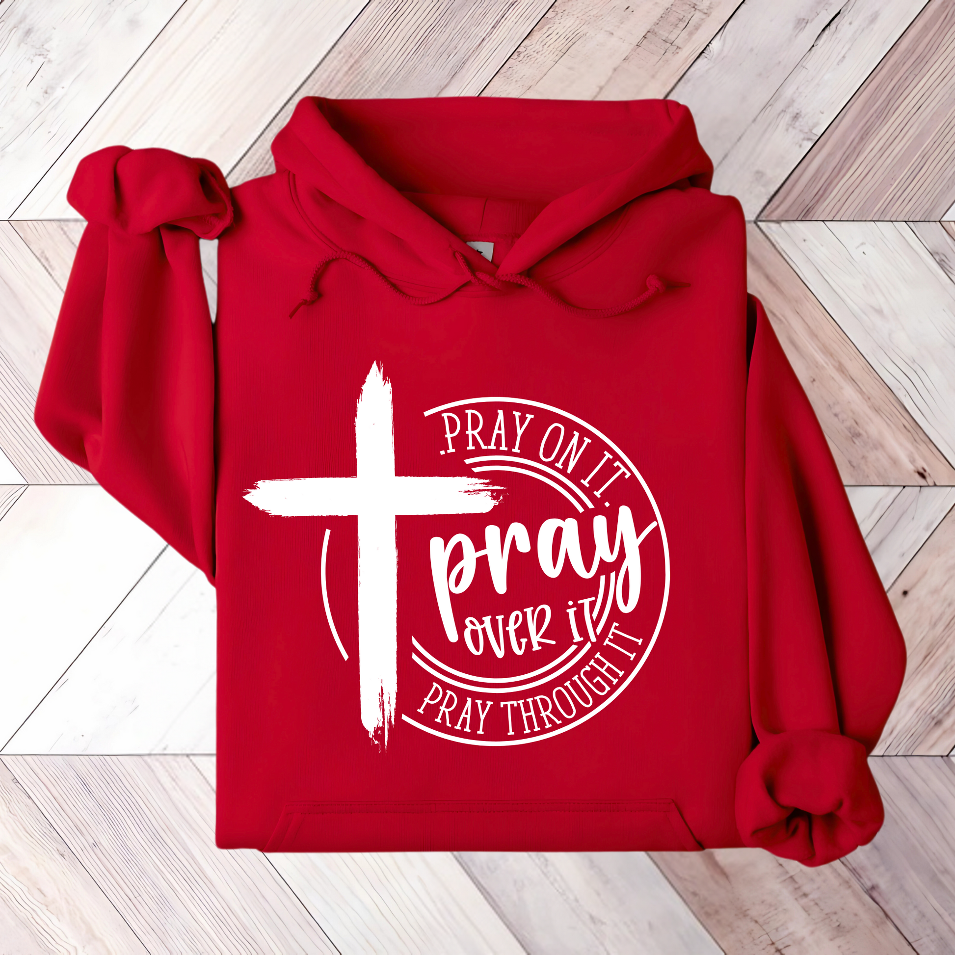 Close-up of a red hoodie with a white cross and ‘Pray Over It’ religious quote.
