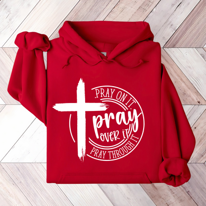 Close-up of a red hoodie with a white cross and ‘Pray Over It’ religious quote.