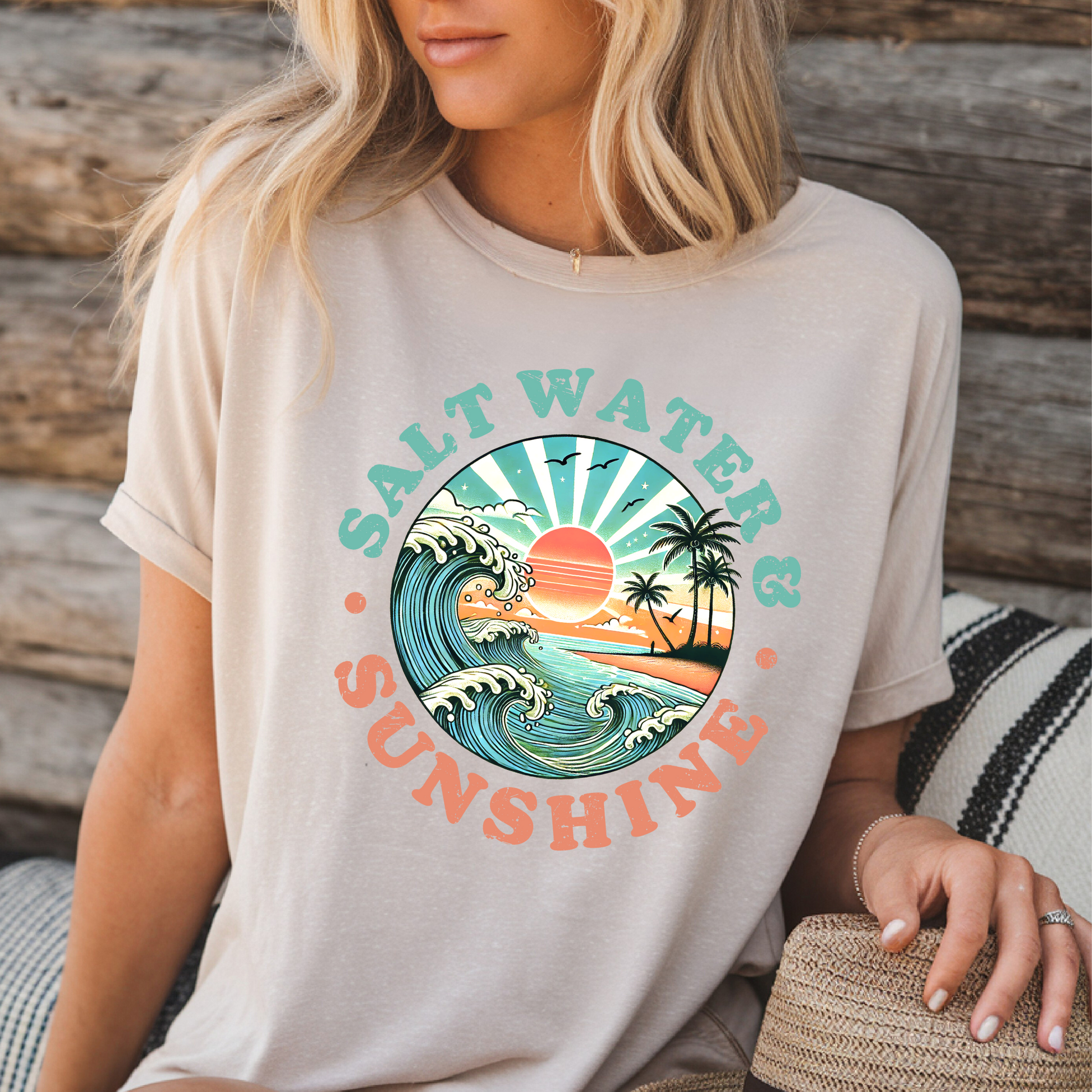 Sand-colored Salt Water & Sunshine tee, woman seated in front of wood background