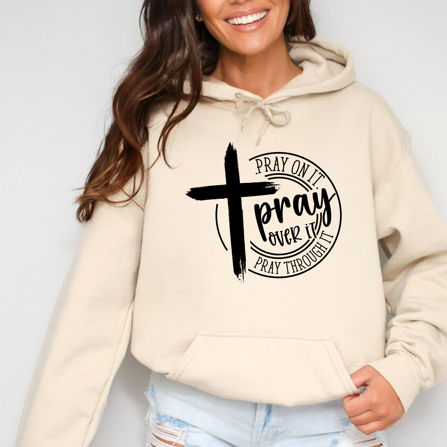 Woman wearing a Sand hoodie with a motivational message and cross symbol.