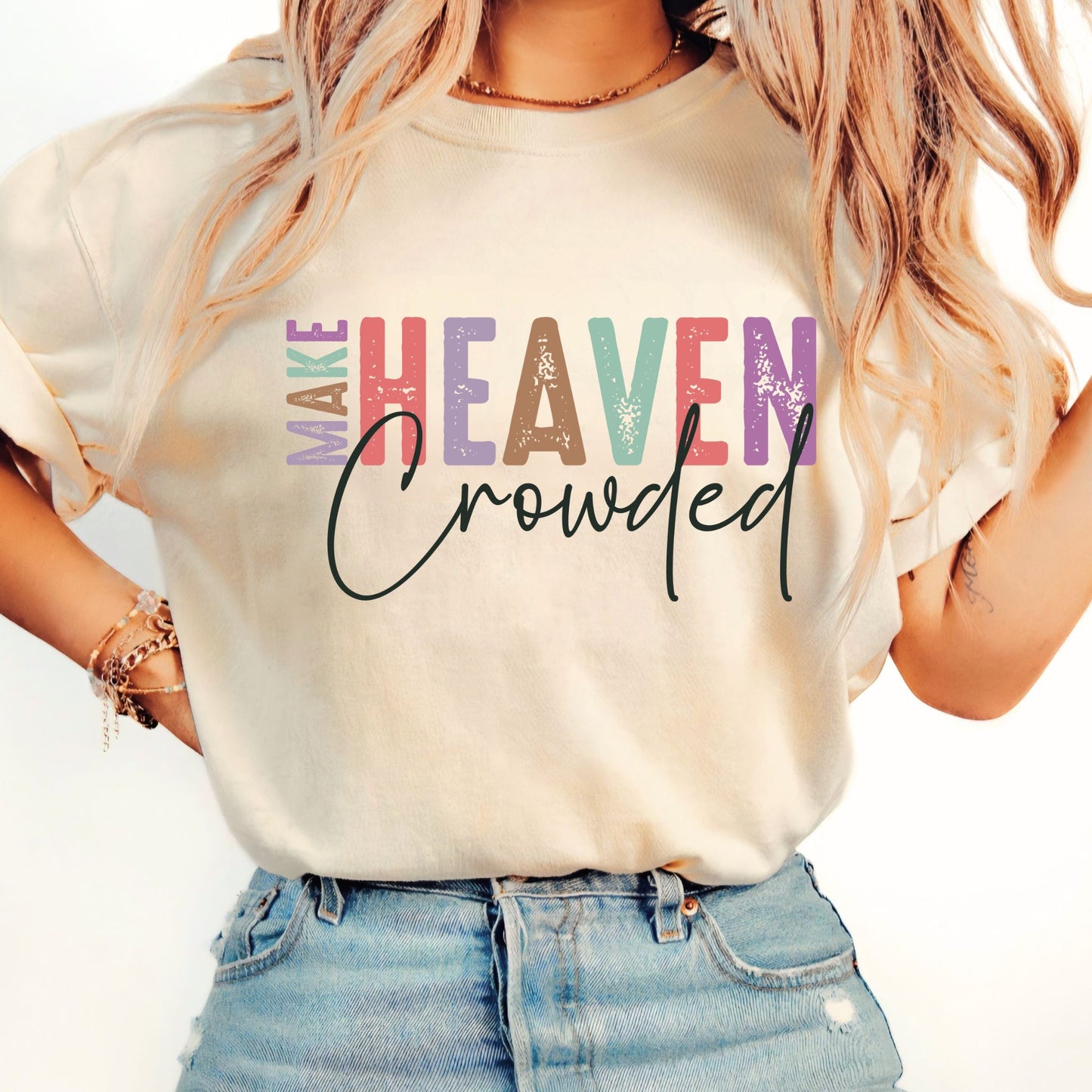 Woman wearing sand-colored Make Heaven Crowded T-shirt with rolled sleeves and denim shorts
