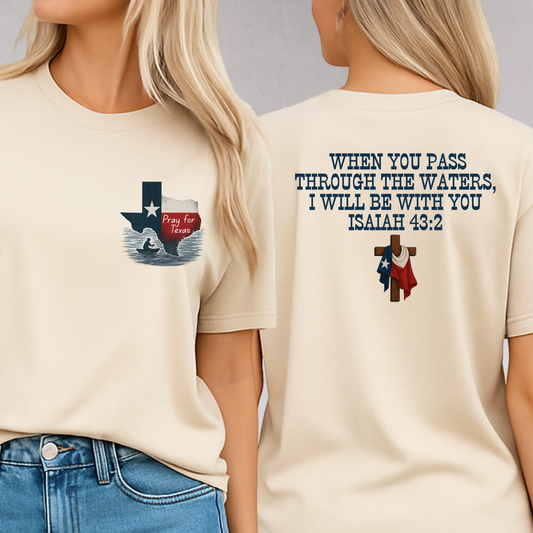 Sand color Christian T-shirt with a front design of Texas state outline and “Pray for Texas” over flood waters. Back displays Isaiah 43:2 scripture with a wooden cross and Texas flag. Support Texas shirt for women.