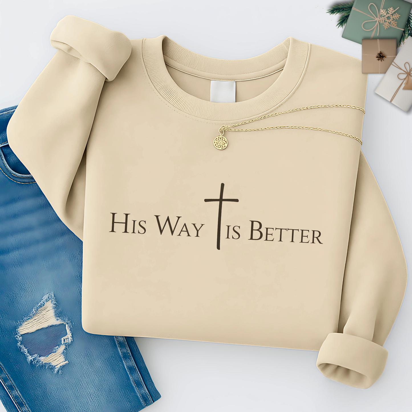 Sand-colored “His Way Is Better” Christian sweatshirt folded with cross design, necklace, and jeans