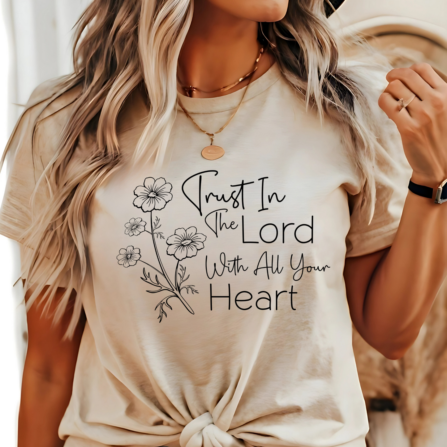 Woman wearing tan T-shirt with floral graphic and “Trust in the Lord With All Your Heart” text.