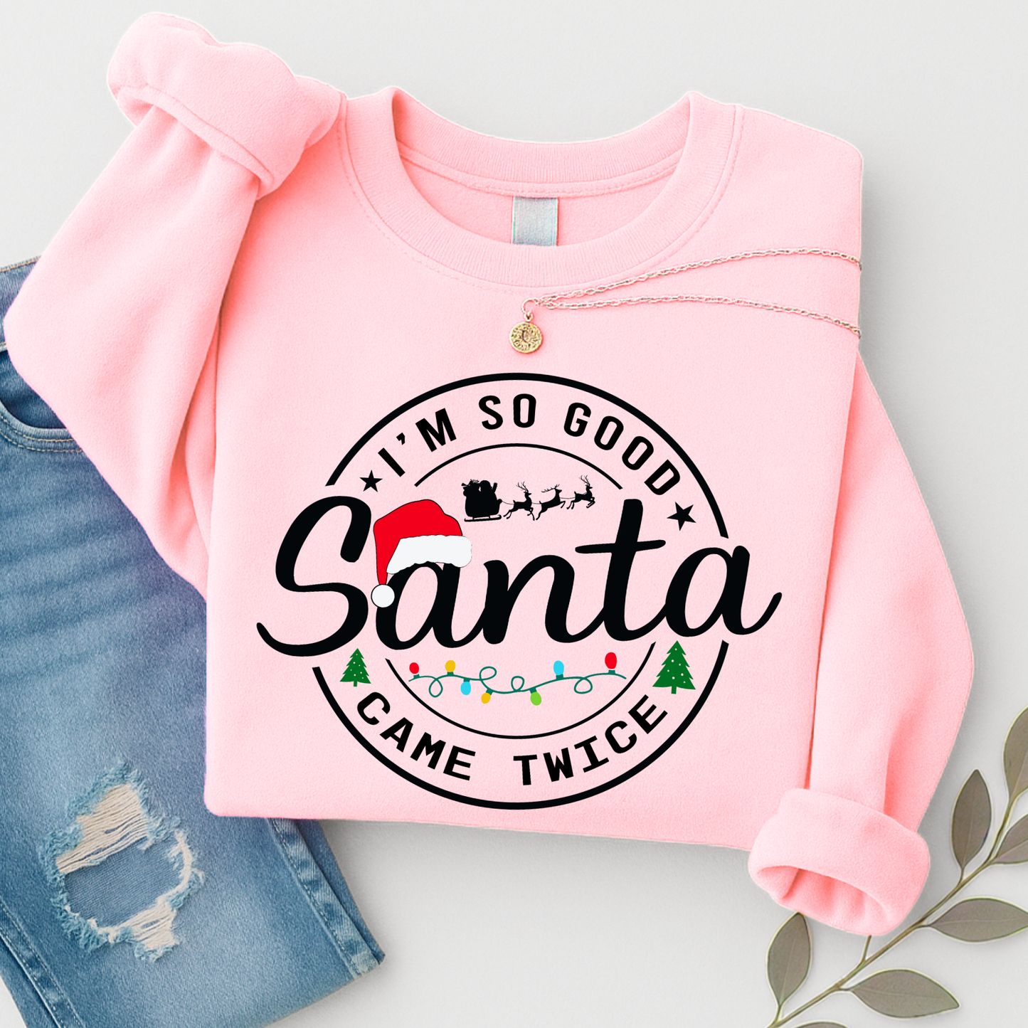 Folded pink Santa Came Twice sweatshirt flat lay with jeans