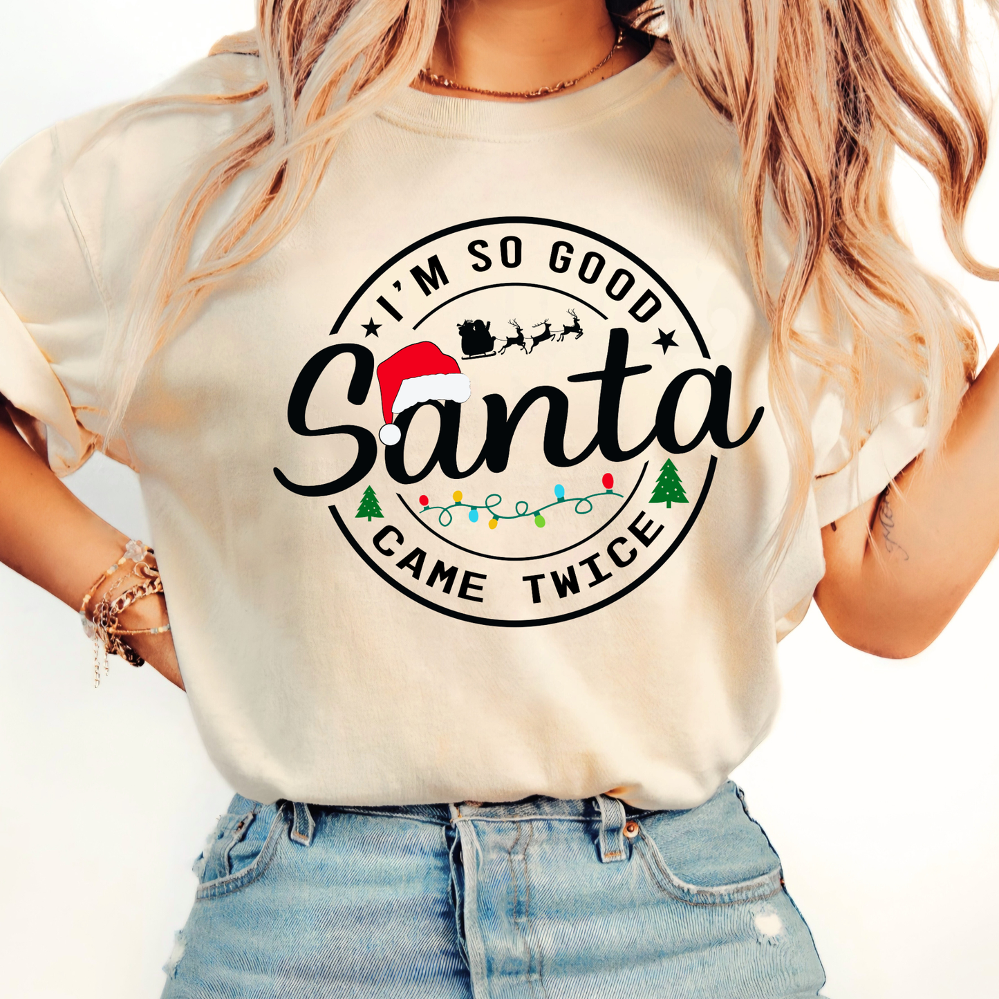 Woman wearing a cream t-shirt with 'I'm so good Santa came twice' text and graphics.