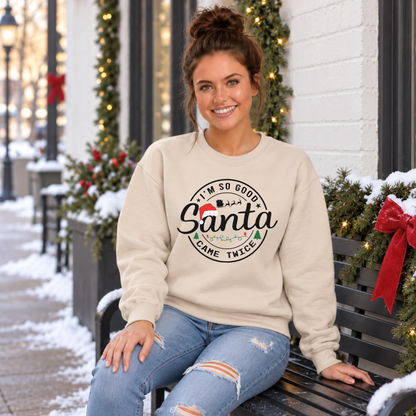 Woman wearing a sand sweatshirt with I'm So Good Santa Came Twice Christmas design on a snowy holiday bench