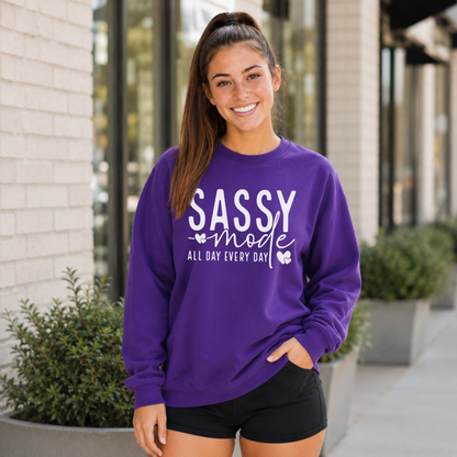 Woman wearing a purple Sassy Mode sweatshirt with white lettering outside a storefront.