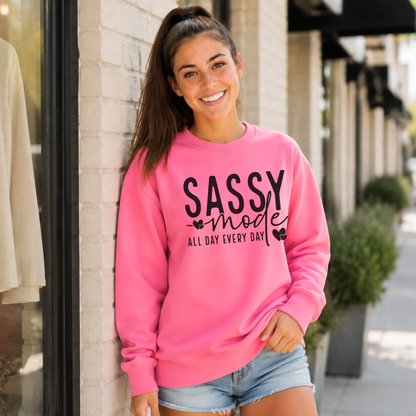 Woman wearing a bright pink Sassy Mode sweatshirt with bold black lettering outside a storefront.