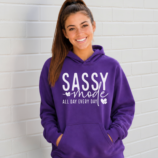 Woman wearing a purple Sassy Mode hoodie with white lettering outside a storefront.