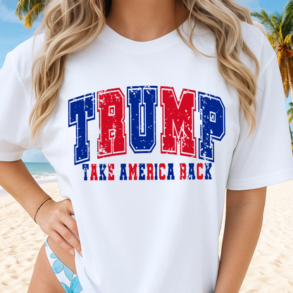 Person wearing a white t-shirt with 'TRUMP TAKE AMERICA BACK' text on a beach.