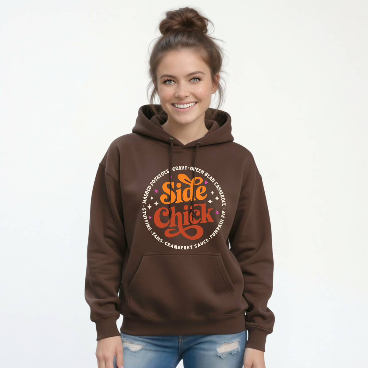 A woman wears a Brown pullover hoodie with the retro “Side Chick” Thanksgiving graphic centered on the chest, paired with blue jeans on a simple white background.