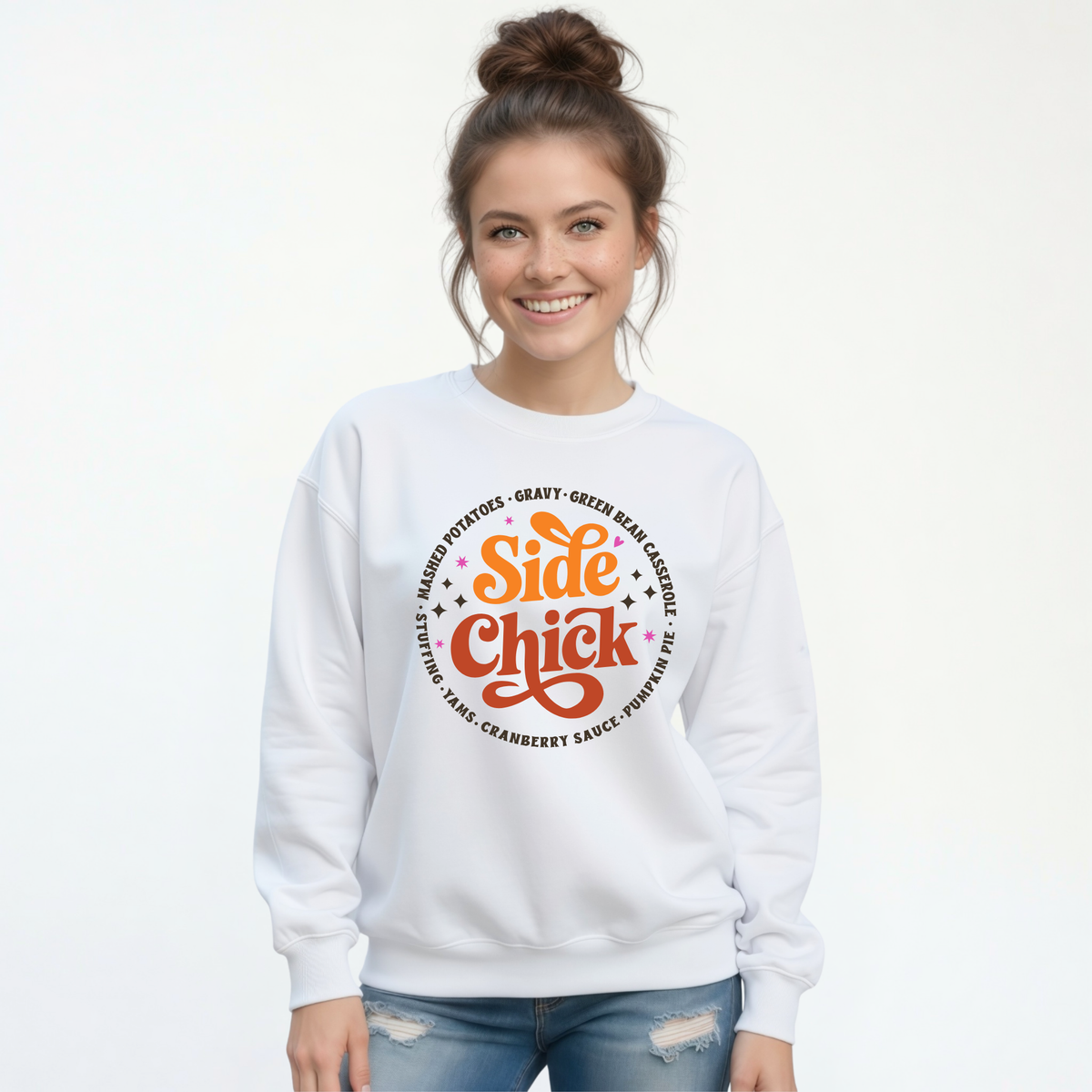 A smiling woman with her hair in a bun wears a White crewneck sweatshirt featuring the retro “Side Chick” Thanksgiving design and dark side-dish lettering against a clean white background.