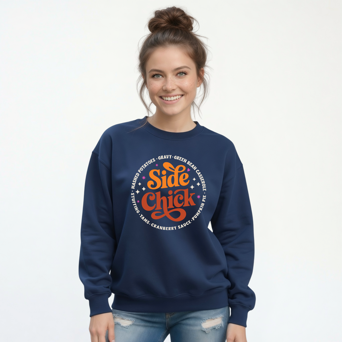 A woman wears a Navy crewneck sweatshirt with the retro “Side Chick” Thanksgiving graphic in bright orange, rust, and light lettering, styled with distressed jeans on a white background.