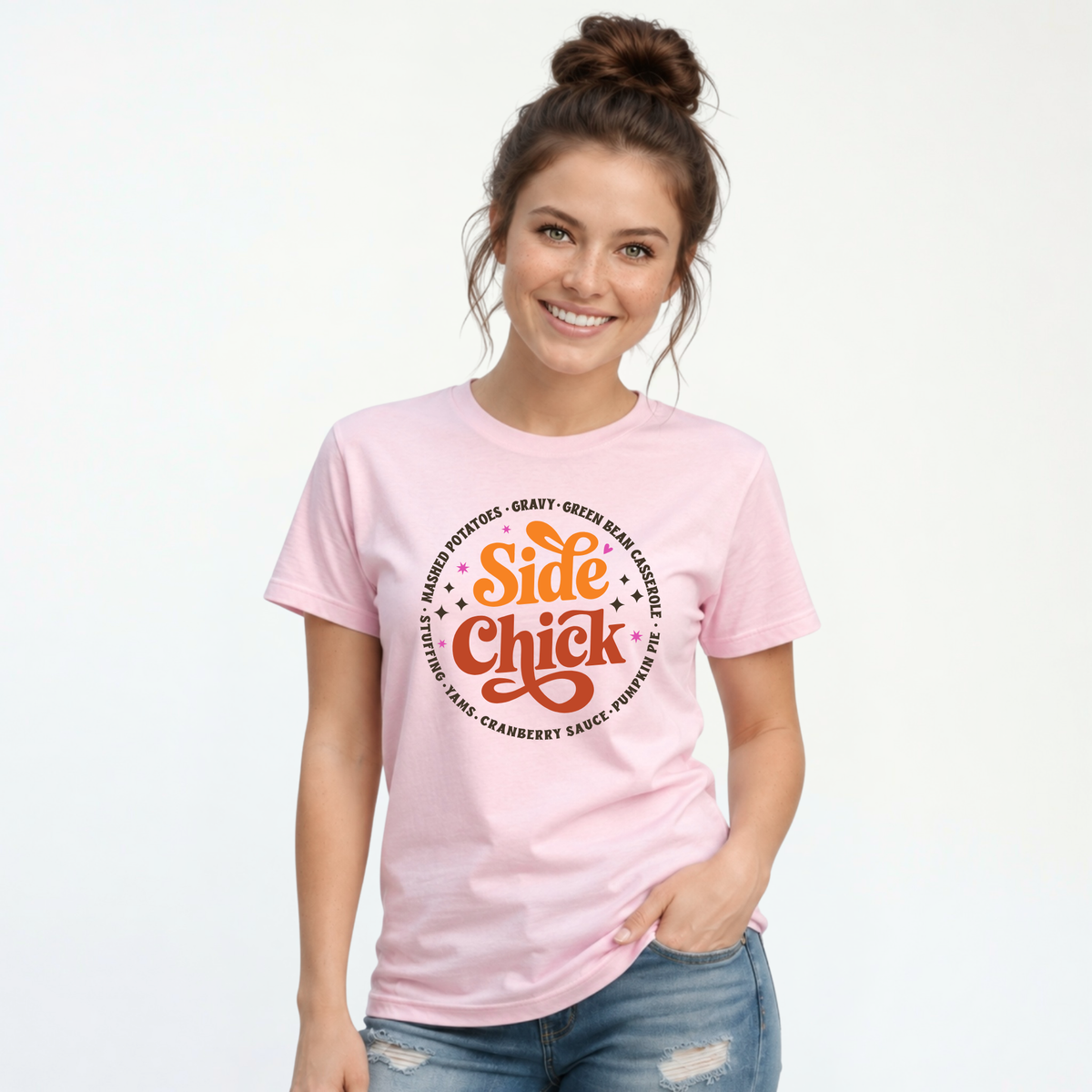 A woman models a Light Pink T-shirt with the retro “Side Chick” Thanksgiving design, dark side-dish lettering, and small star accents against a bright white background.