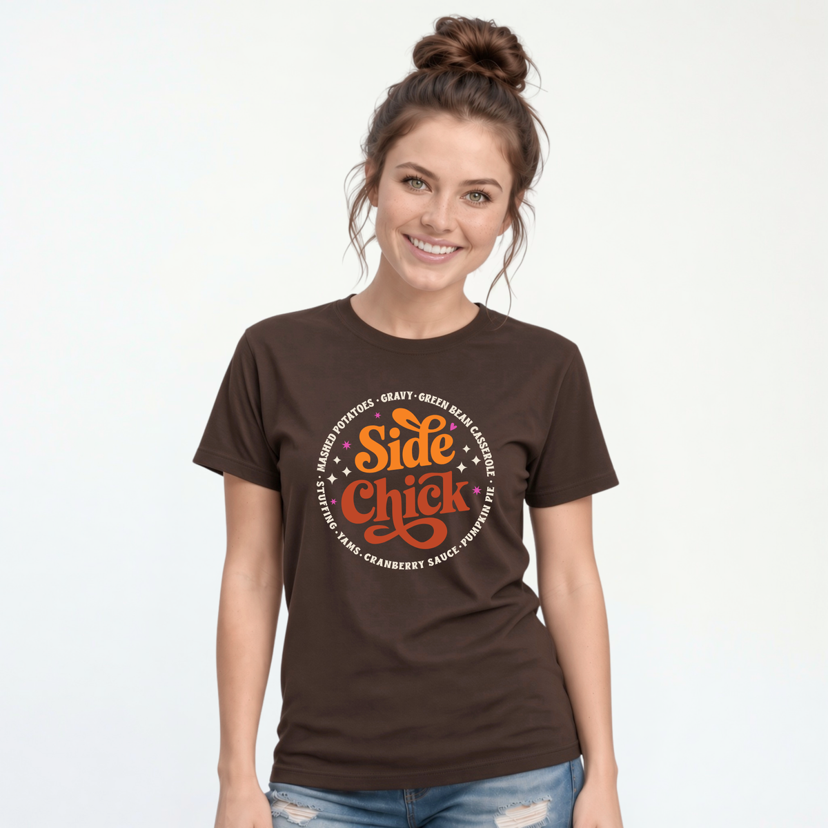 A woman models a Brown T-shirt with the funny retro “Side Chick” Thanksgiving design and light circular side-dish text against a clean studio background.