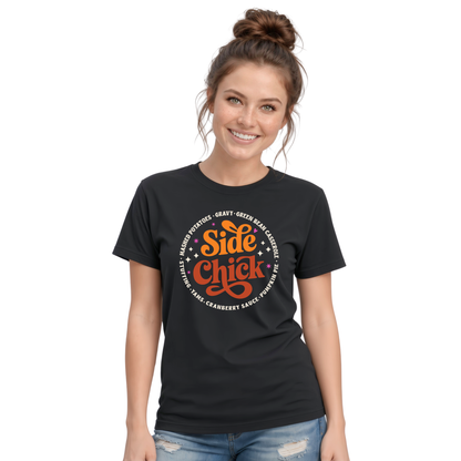 A woman models a Black T-shirt with the retro “Side Chick” Thanksgiving graphic in orange and light lettering, surrounded by classic side-dish names, against a clean white background.