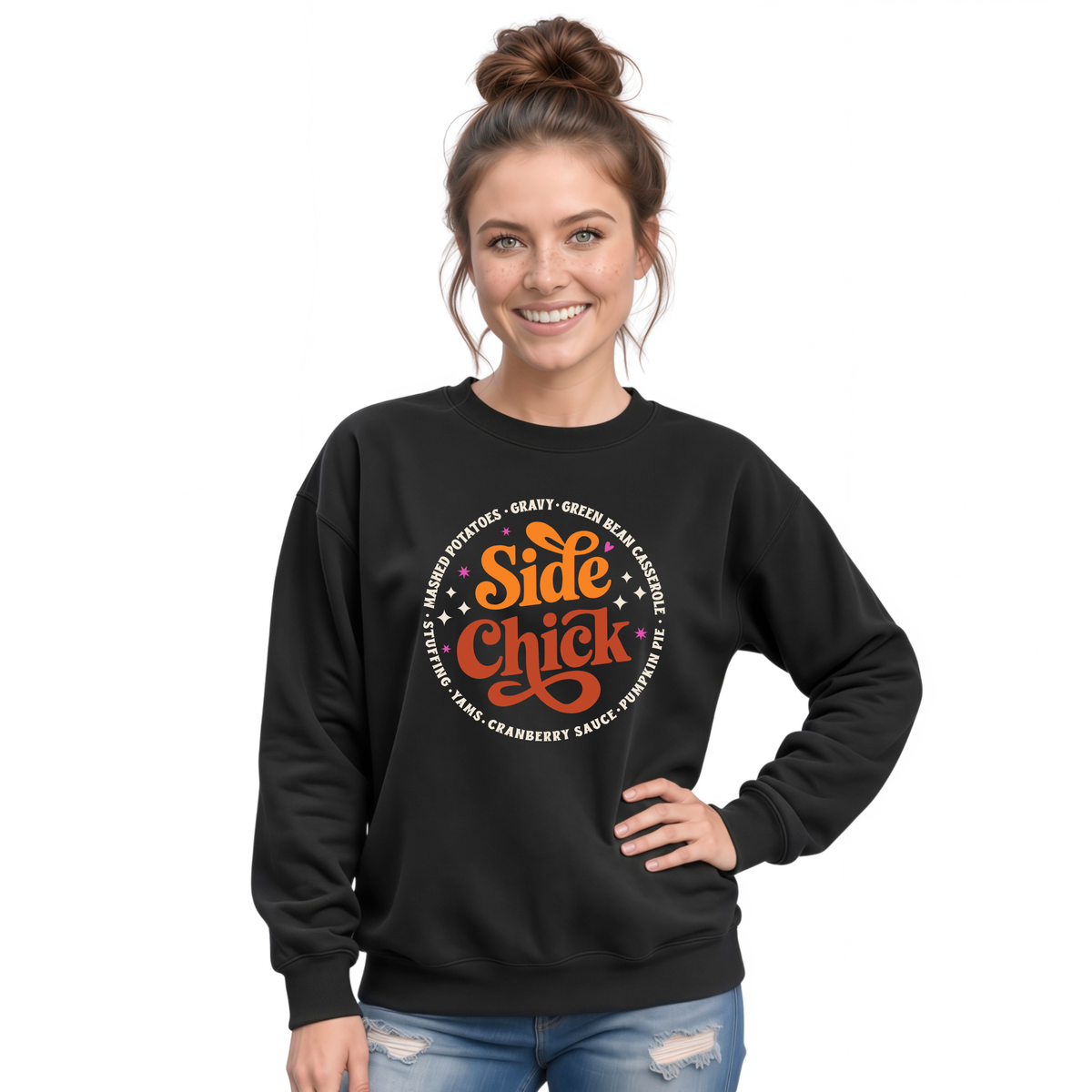 A woman wears a Black crewneck sweatshirt featuring the retro “Side Chick” Thanksgiving design with bright orange and light lettering and circular side-dish text on a white studio background.