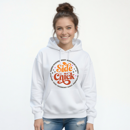 A smiling woman wears a White pullover hoodie with the orange-and-rust “Side Chick” Thanksgiving design, surrounded by dark side-dish lettering on a clean studio background.