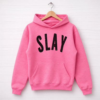 Bright pink SLAY hoodie hanging on a wooden hanger with bold black distressed lettering.