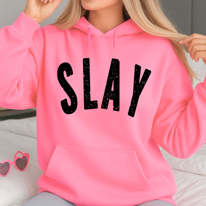 Person wearing a pink hoodie with 'SLAY' text, sitting on a light-colored surface.