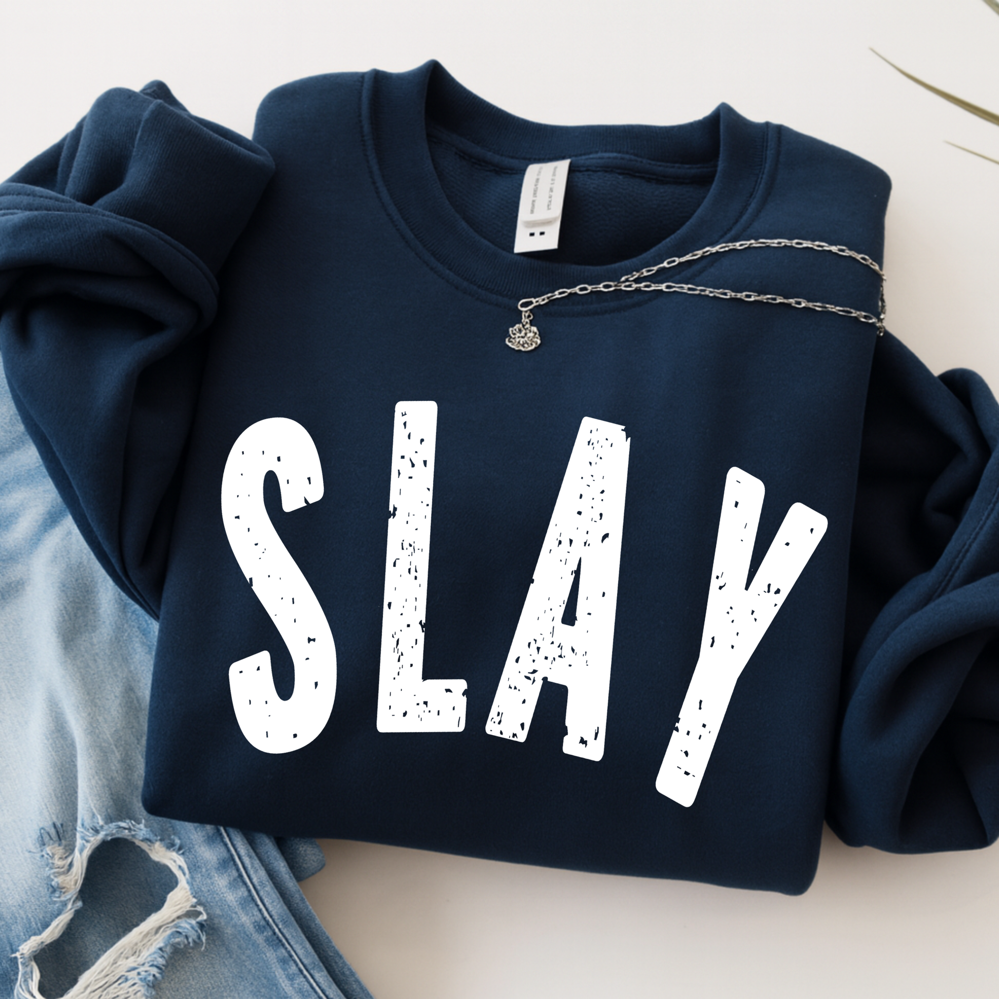 Navy blue sweatshirt with 'SLAY' text on a light background