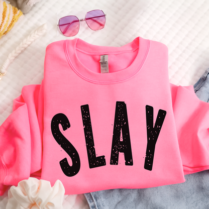 Flat lay bright pink SLAY sweatshirt folded with sunglasses and denim