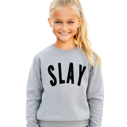 Girl wearing gray SLAY sweatshirt smiling outdoors