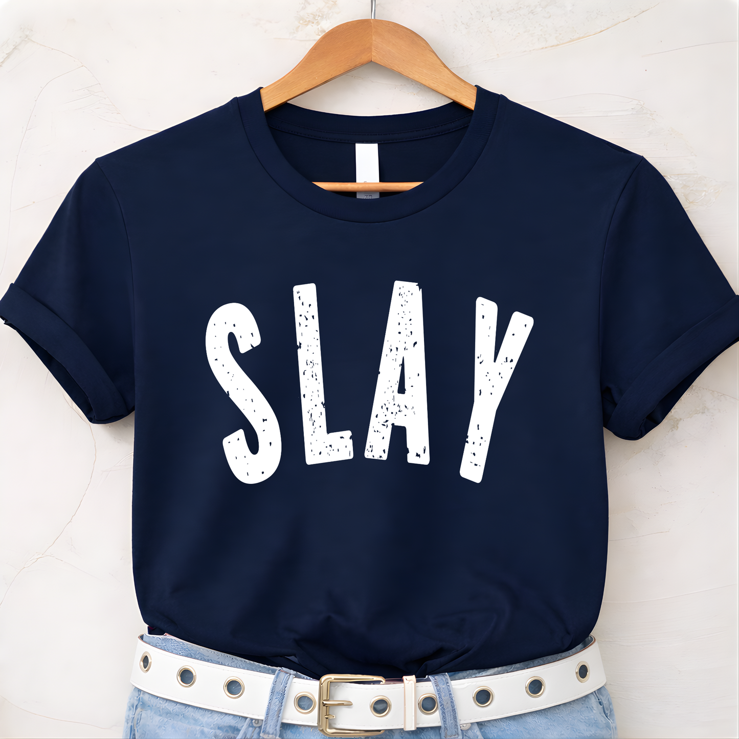 Navy blue t-shirt with 'SLAY' text on a hanger against a white background