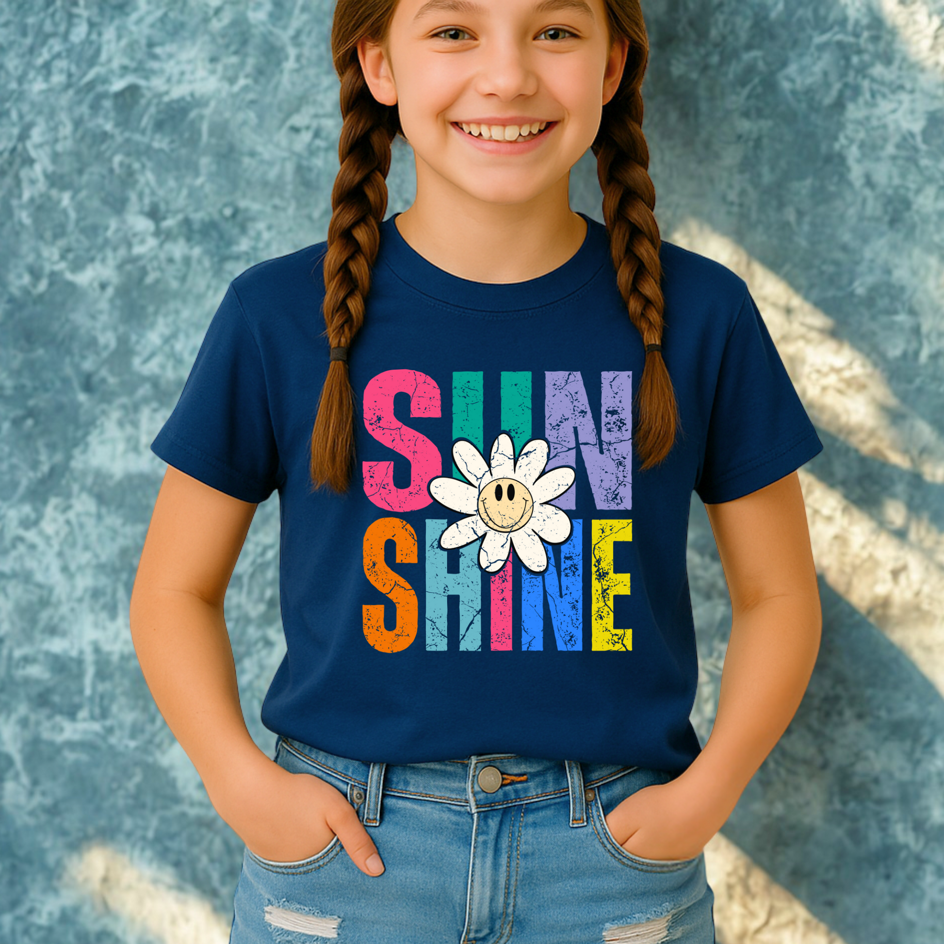 Smiling girl wearing a Navy Blue Sunshine T-shirt with a retro daisy and rainbow letters
