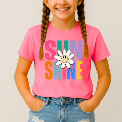 Smiling girl wearing a bright pink Sunshine T-shirt with a retro daisy and rainbow letters

