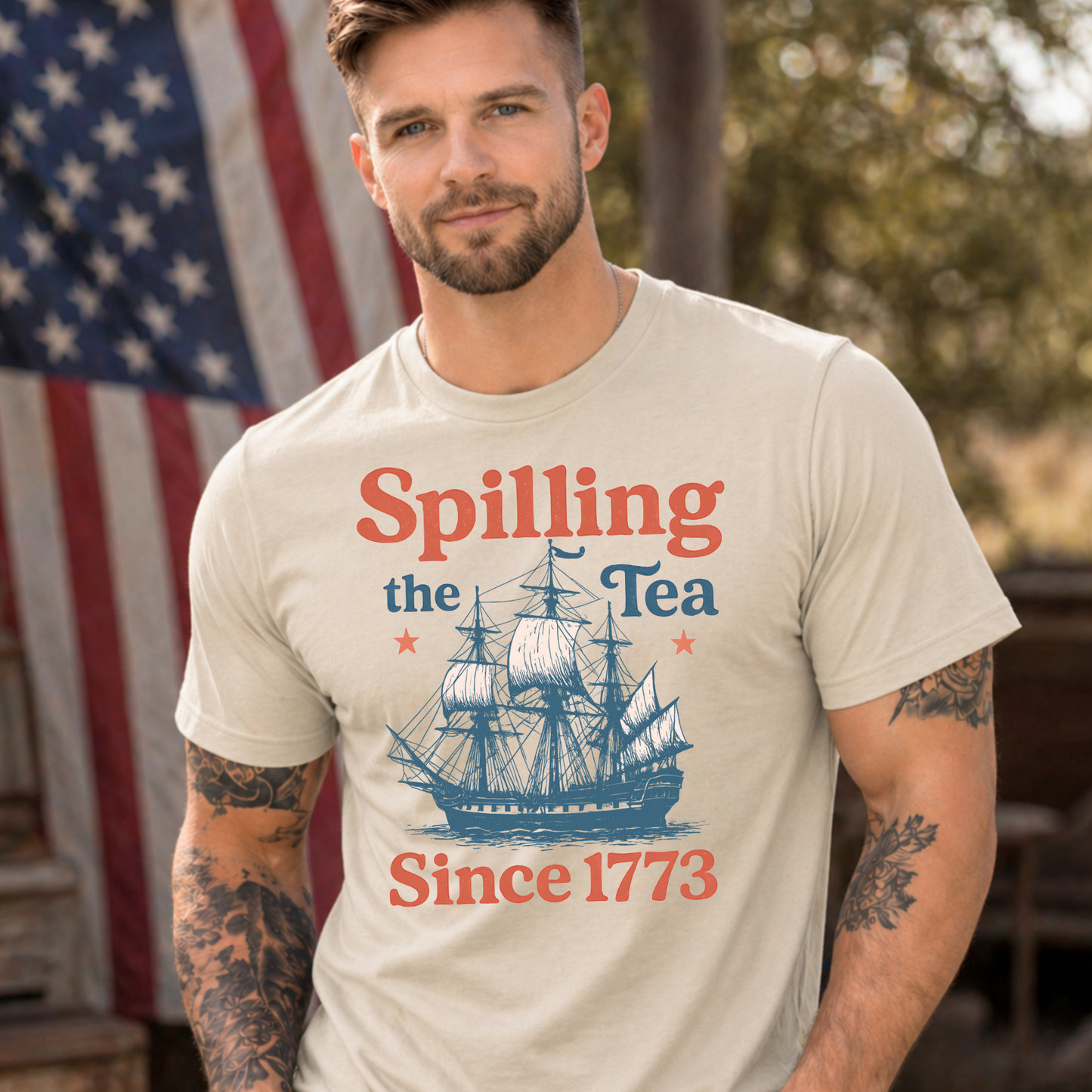 Man wearing a t-shirt with 'Spilling the Tea Since 1773' design in front of an American flag.