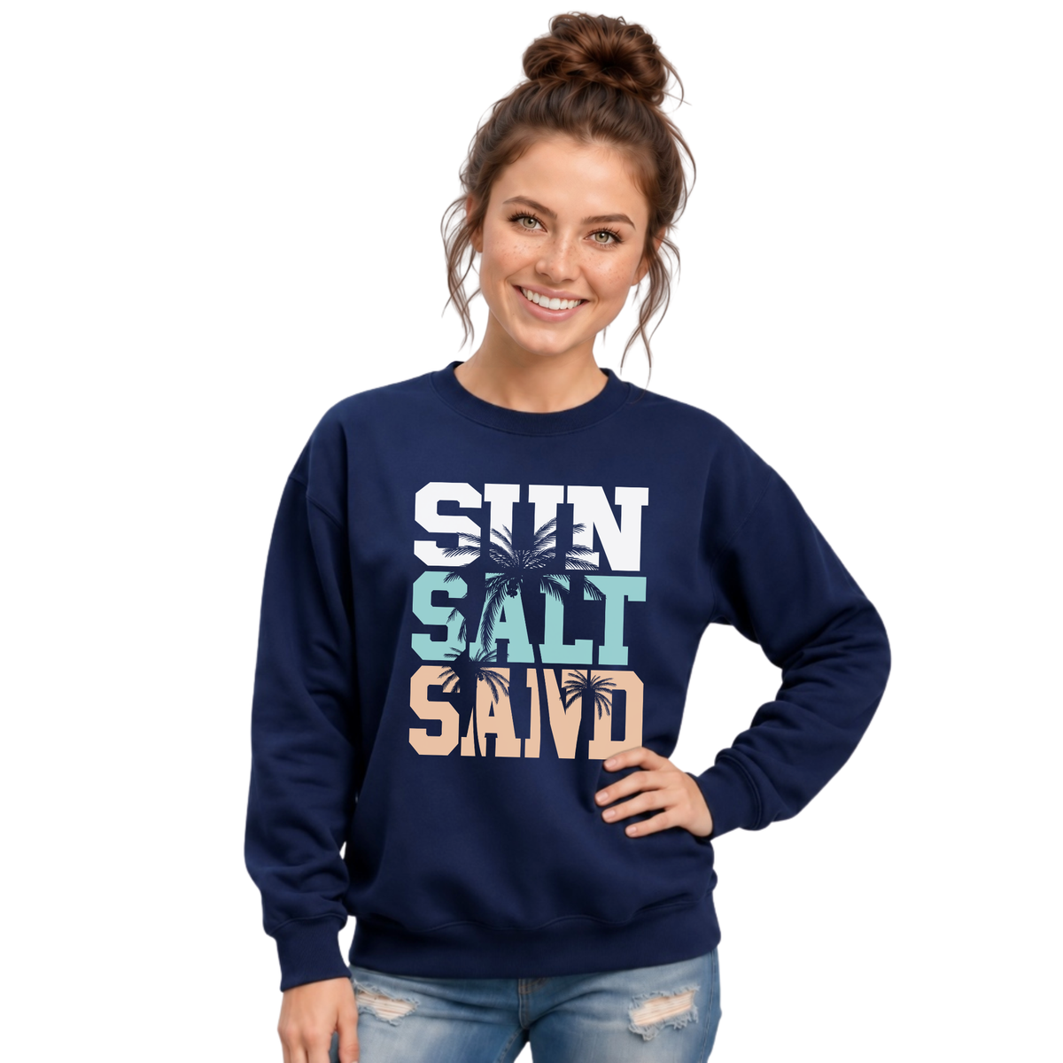Side-by-side views of a woman wearing a navy crewneck sweatshirt with a stacked Sun Salt Sand graphic in white, aqua, and peach with dark palm trees.