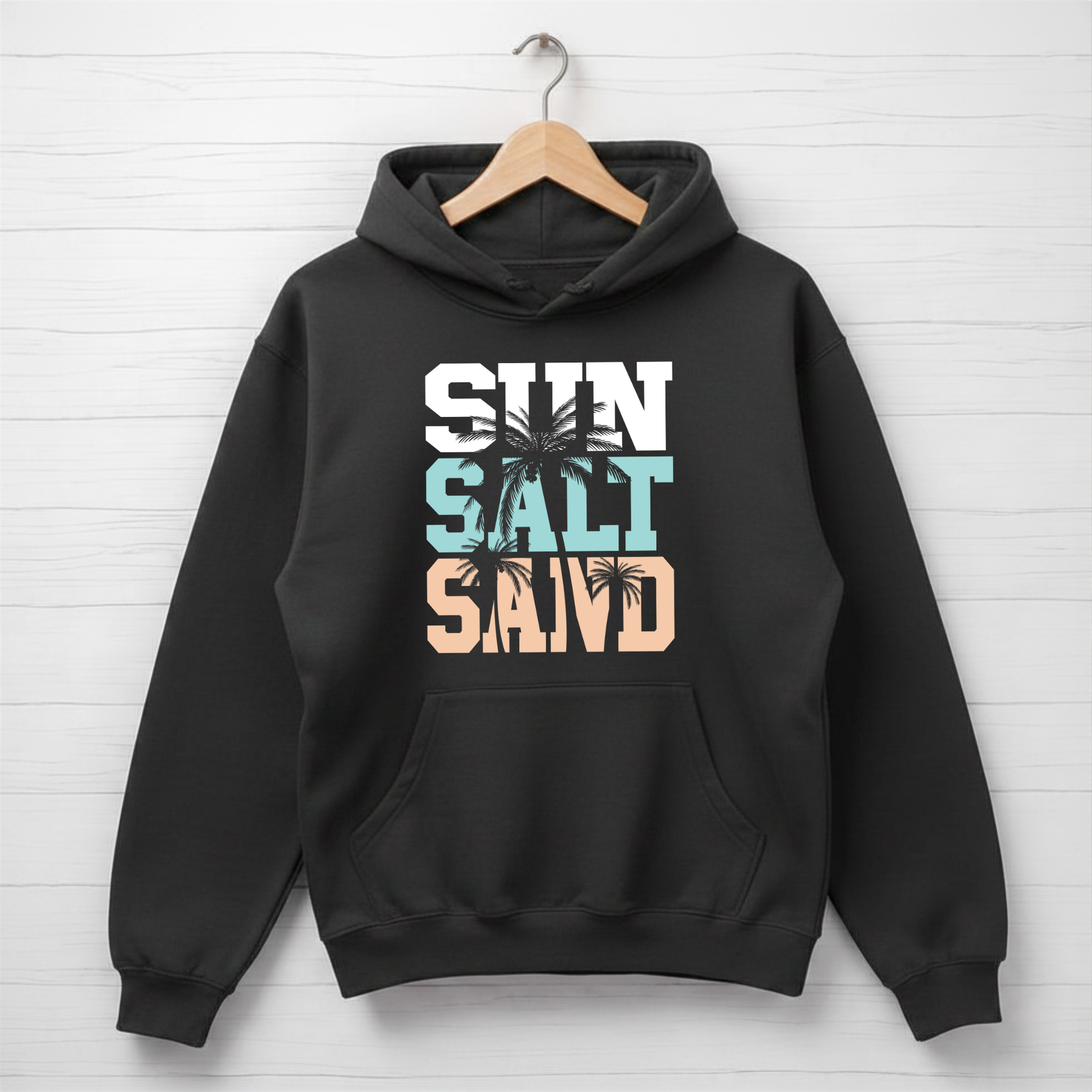 Black hoodie with 'Sun Salt Sand' text and palm trees on a white wooden background