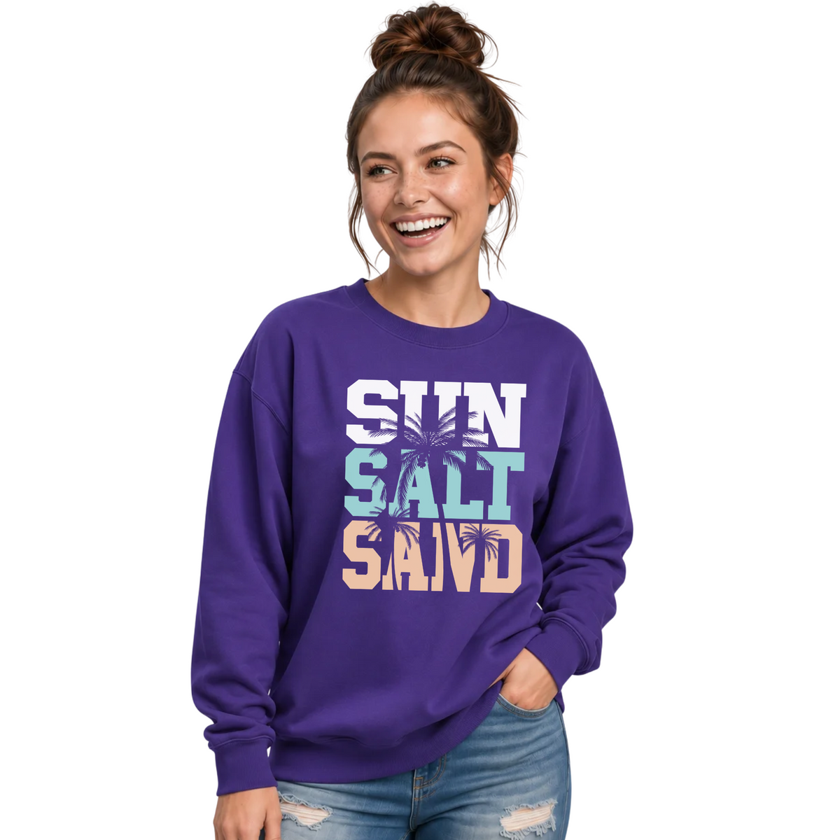 Side-by-side views of a woman wearing a purple crewneck sweatshirt with a stacked Sun Salt Sand graphic in white, aqua, and peach with dark palm trees.